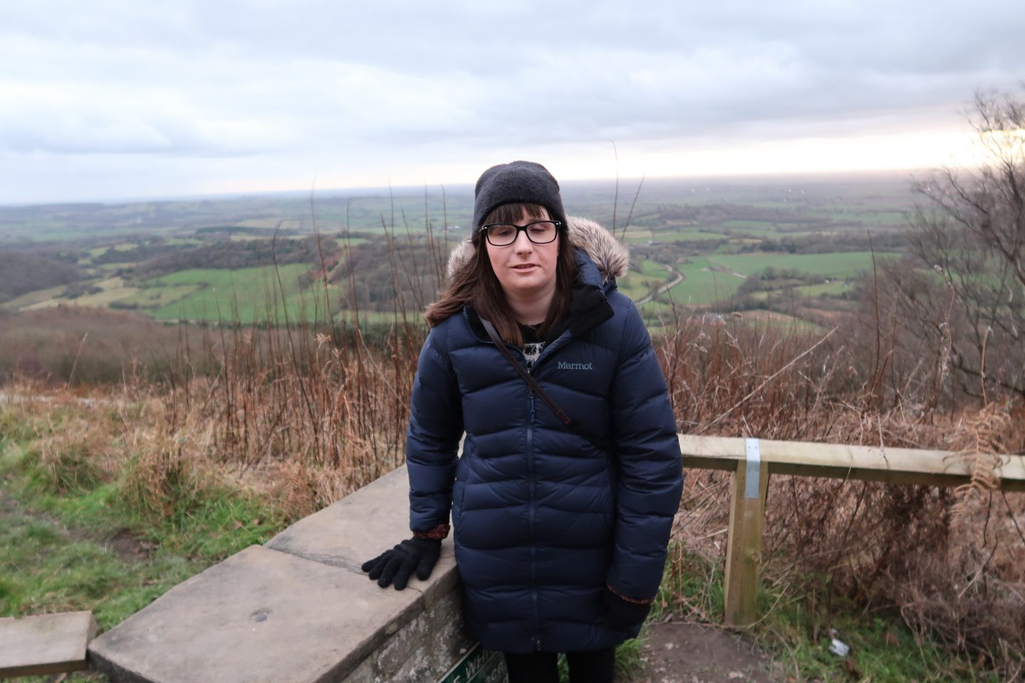 A photo of Holly stood, there are fields in the background