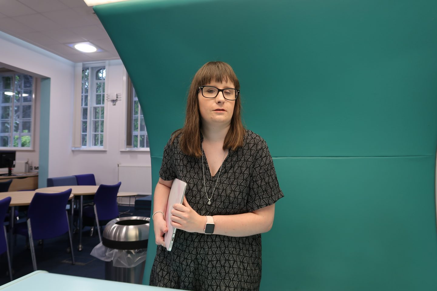 A photo of Holly stood up with her laptop under her arm
