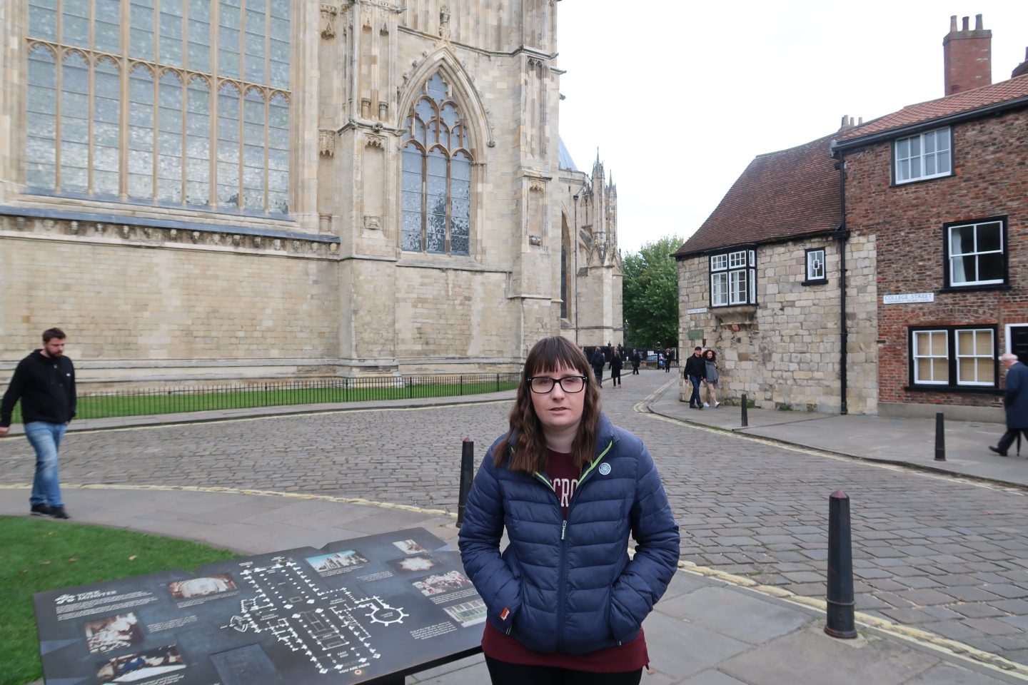 A photo of holly stood in front of York Minster with a tourist information map behind her, there is a cobbled street and houses in the background