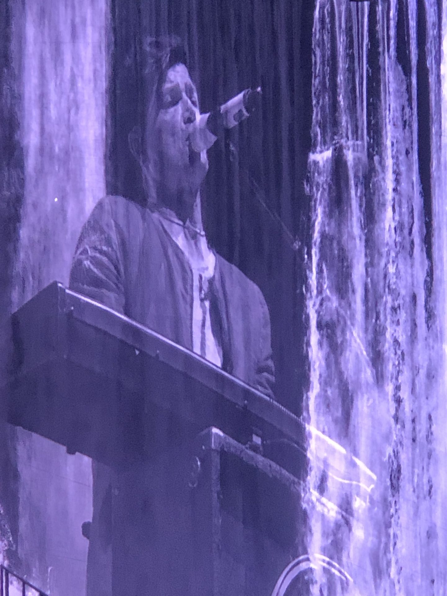 A backdrop image of Danny O'Donoghue singing and playing a keyboard with a special effect of water in the background
