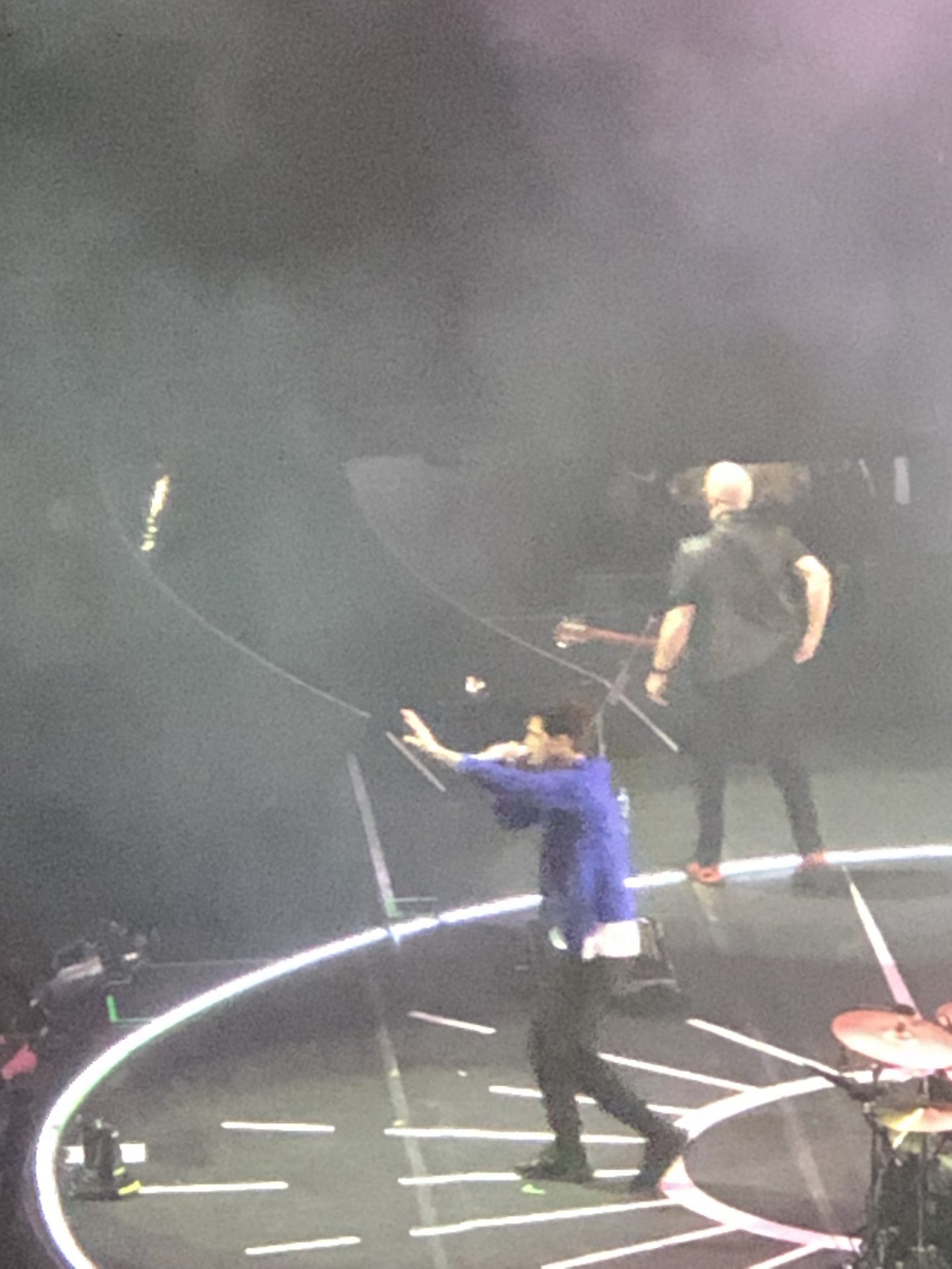 Danny O'Donoghue and Mark Sheehan. Danny is singing and holding a microphone with his left arm out whilst Mark is playing the guitar at the left-hand side of the stage