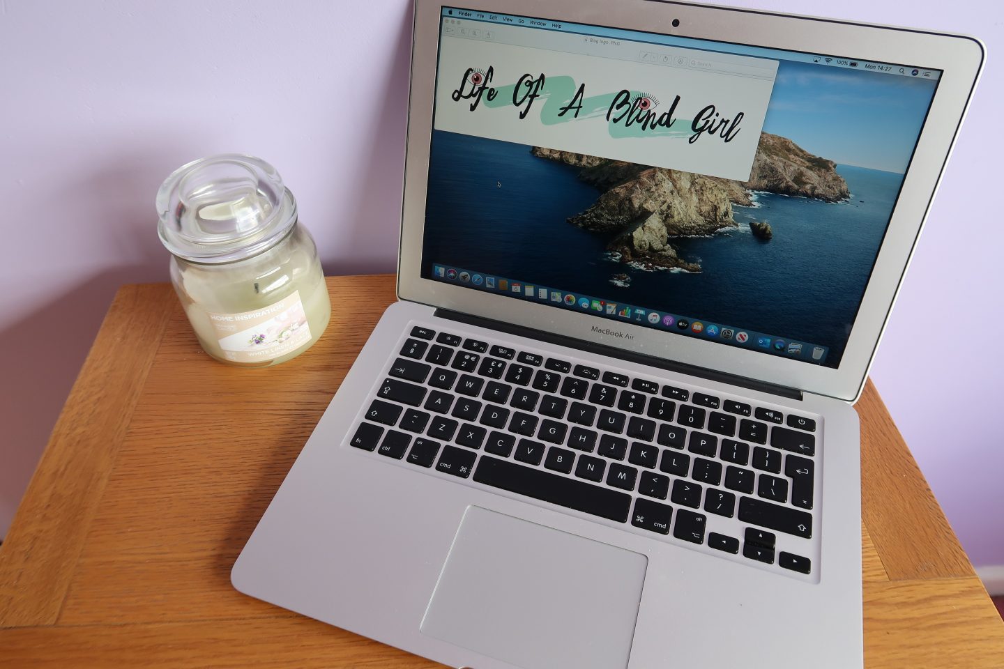 Holly's blog logo on a MacBook screen with a candle at the side on a table