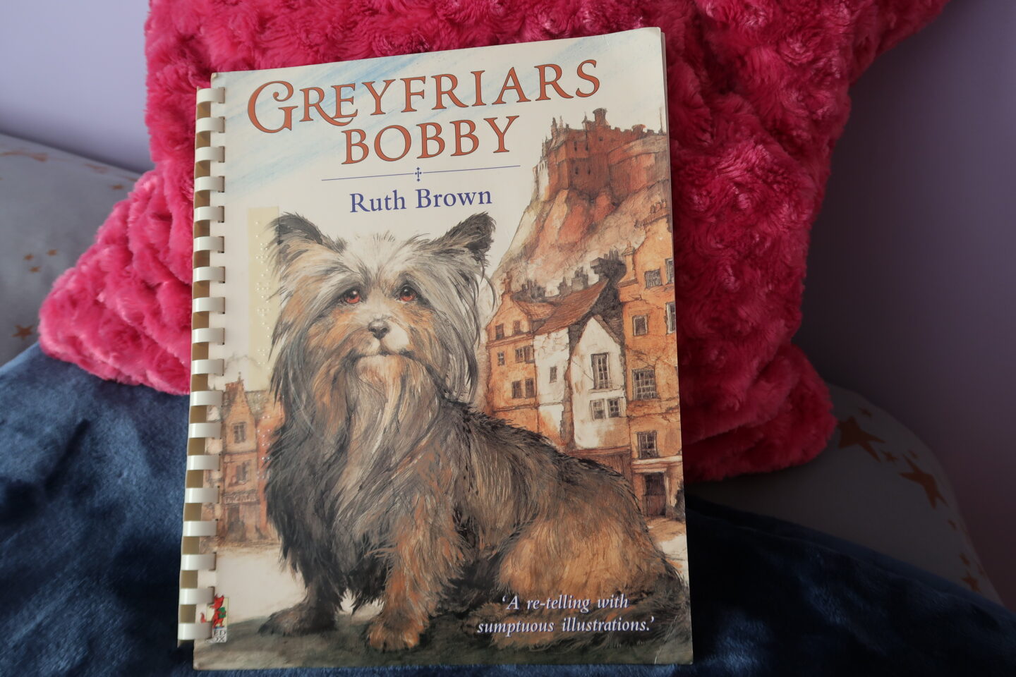 Braille version of the book Greyfriars Bobby, there is a picture of a dog sat behind a building on the cover