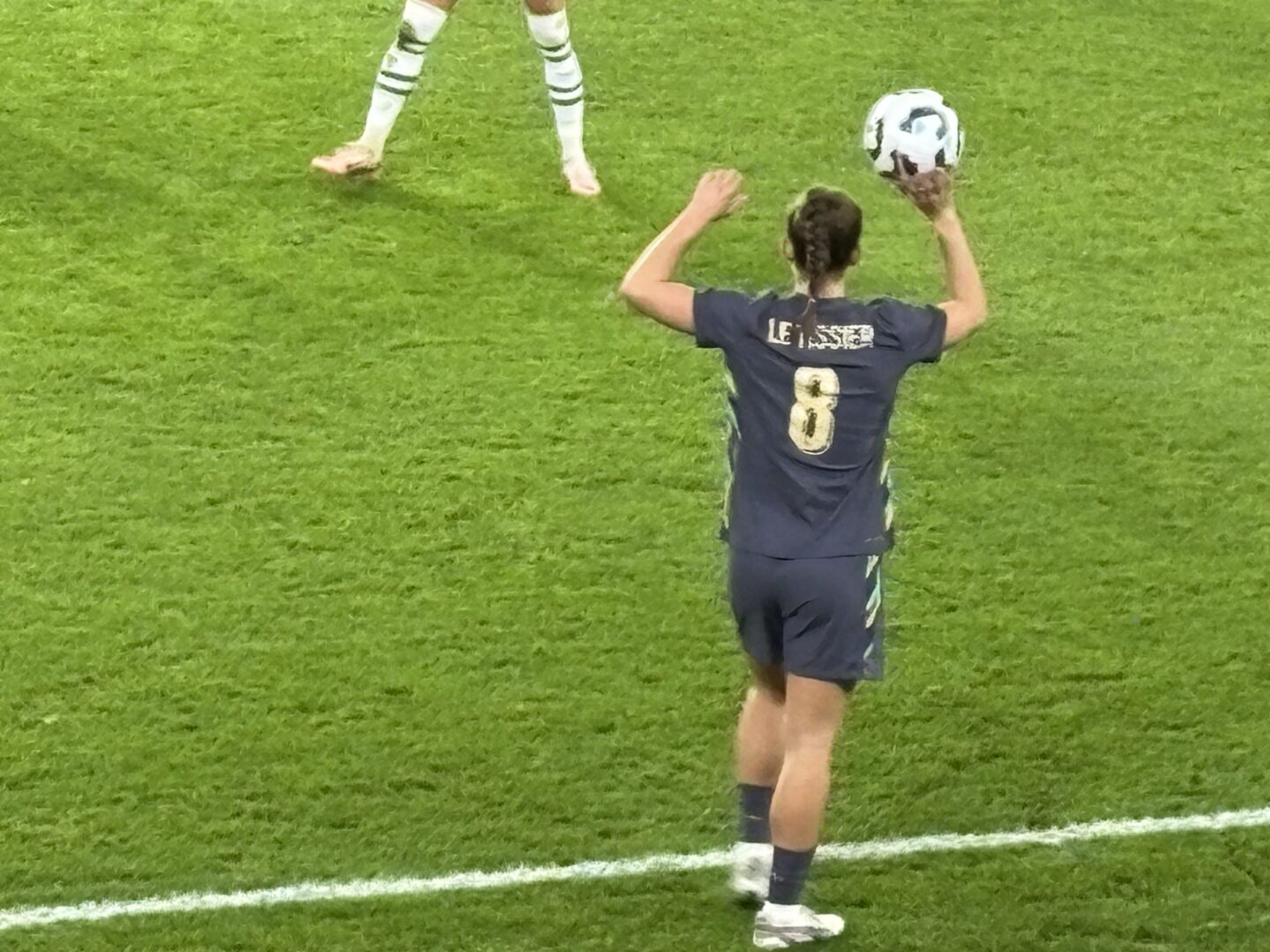 Close-up photo of Maya Le Tissier taking a throw-in on the touchline. She's wearing the purple England away kit.